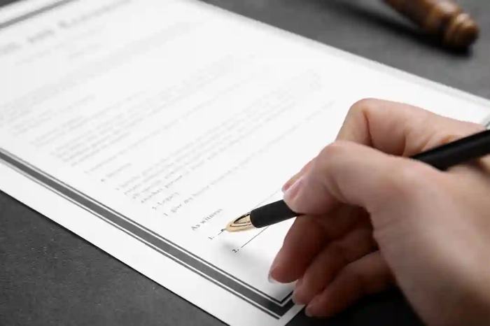 Assinatura final de um Contrato em Licitação sendo registrada com caneta sobre documento formal, em momento decisivo de validação jurídica.