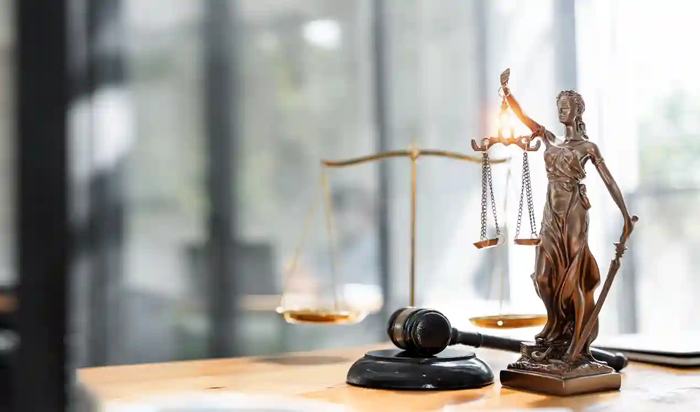Estátua da Justiça com balança e martelo sobre mesa de tribunal, representando o reequilíbrio contratual e a recomposição do equilíbrio econômico-financeiro nos contratos administrativos.