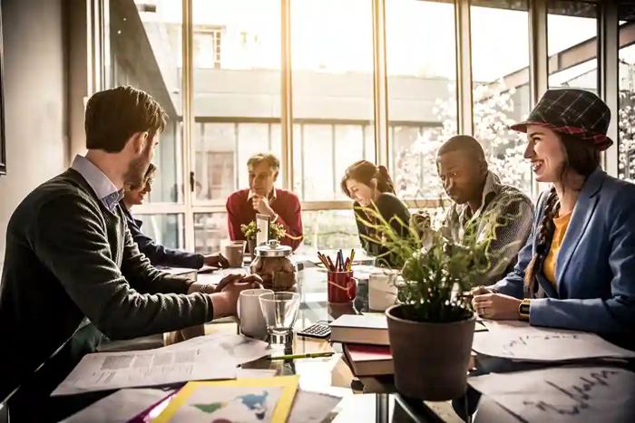 Grupo multicultural reunido em mesa corporativa com documentos, gráficos e laptops, em ambiente urbano moderno, simbolizando negociações, estratégias jurídicas e acordos institucionais ligados a licitações para empresas estrangeiras.